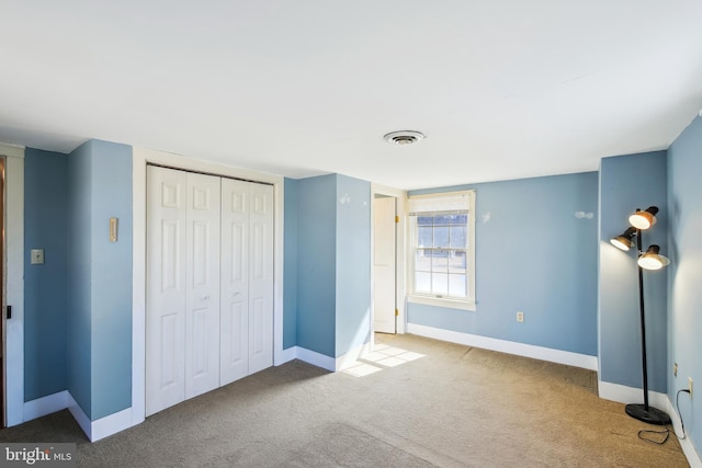 unfurnished bedroom with a closet, carpet flooring, visible vents, and baseboards