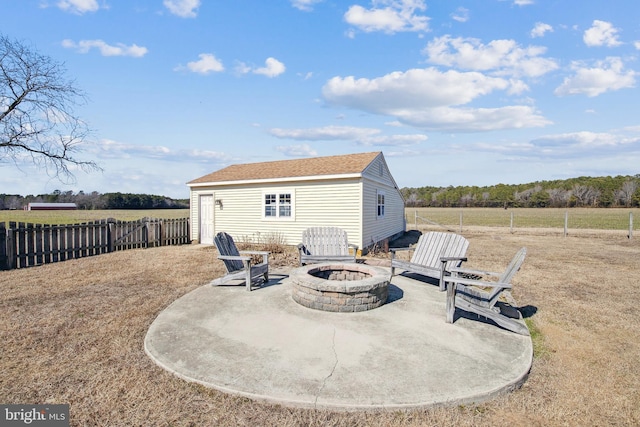 back of property with an outdoor fire pit, a shingled roof, an outbuilding, fence, and a patio area