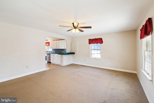 unfurnished living room with ceiling fan, light colored carpet, and baseboards