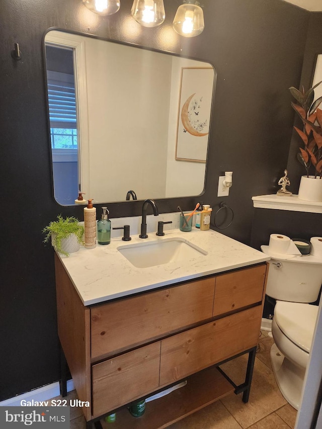 half bath featuring tile patterned floors, toilet, and vanity