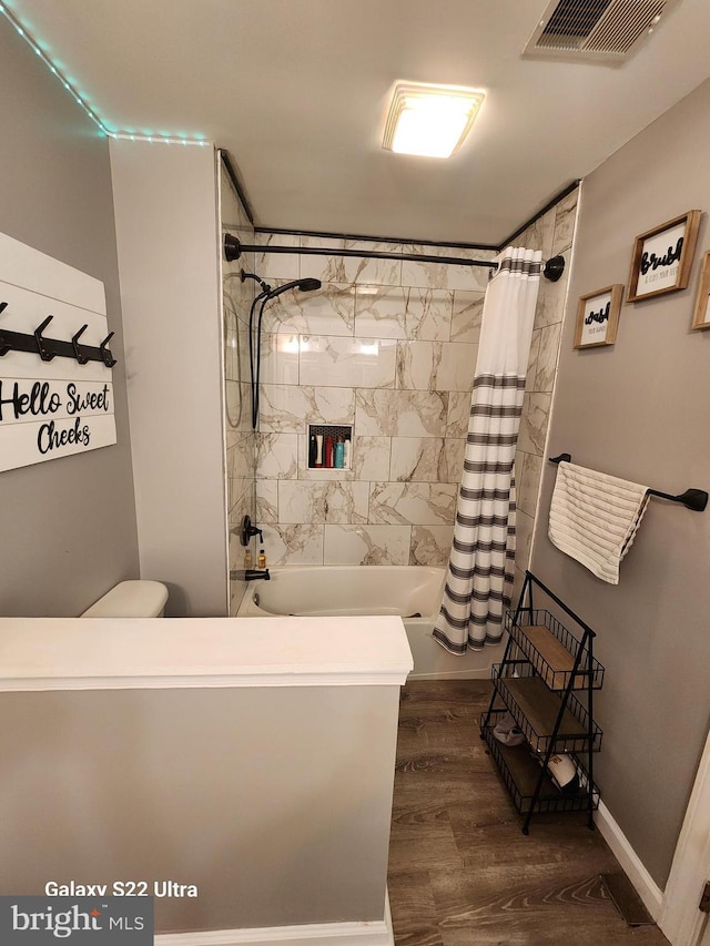 full bath with visible vents, shower / tub combo with curtain, toilet, wood finished floors, and baseboards