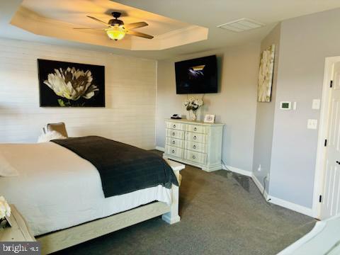 carpeted bedroom with a tray ceiling, baseboards, and a ceiling fan