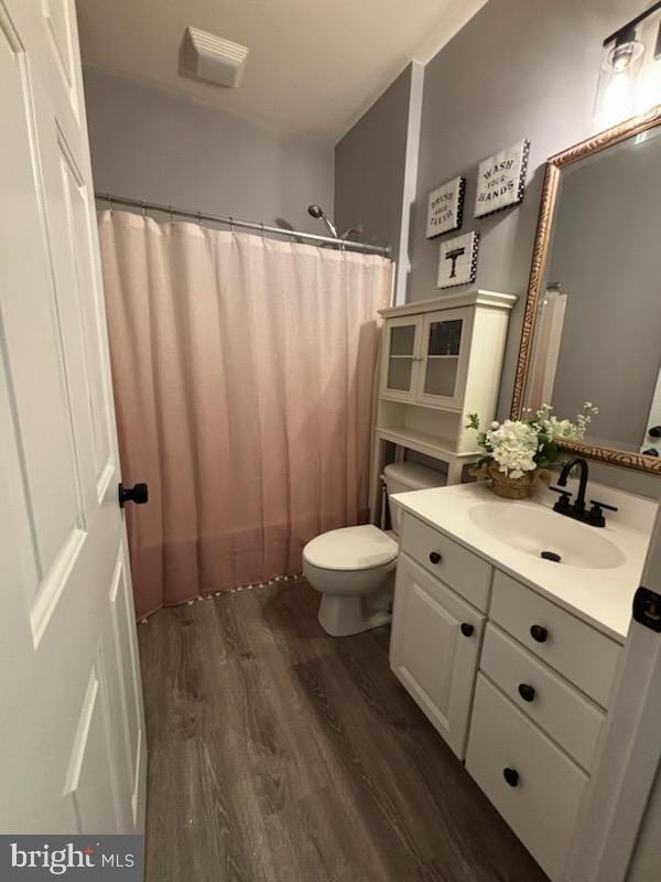 full bathroom featuring vanity, a shower with curtain, toilet, and wood finished floors