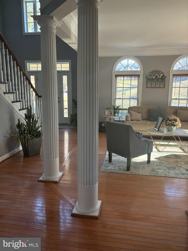 living room featuring hardwood / wood-style flooring, crown molding, and ornate columns