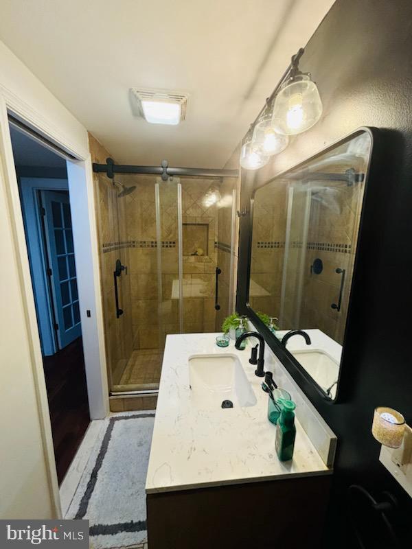 full bathroom with vanity, a shower stall, and visible vents