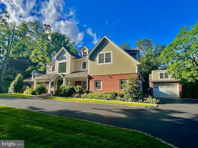 view of front of home with an attached garage, aphalt driveway, a front lawn, and brick siding