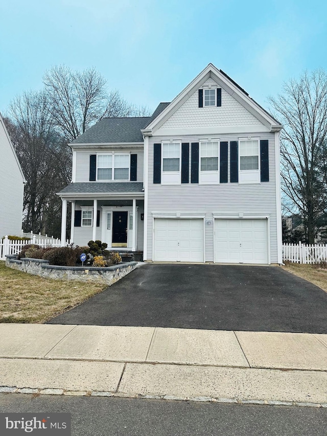 traditional home featuring aphalt driveway, fence, and an attached garage