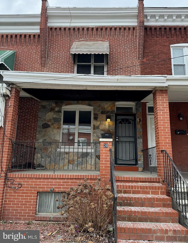 entrance to property featuring covered porch and brick siding