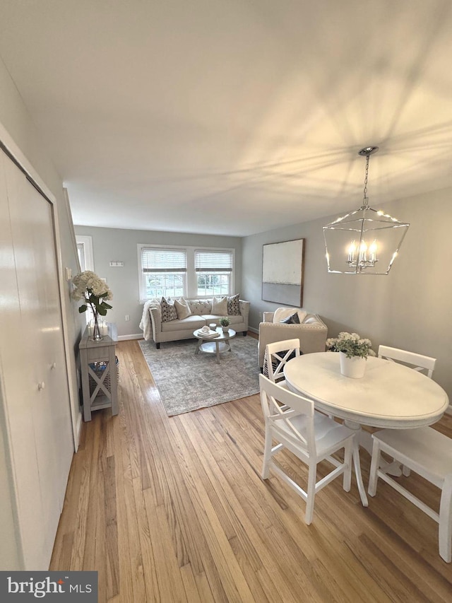 dining space featuring light wood-style floors, a chandelier, and baseboards