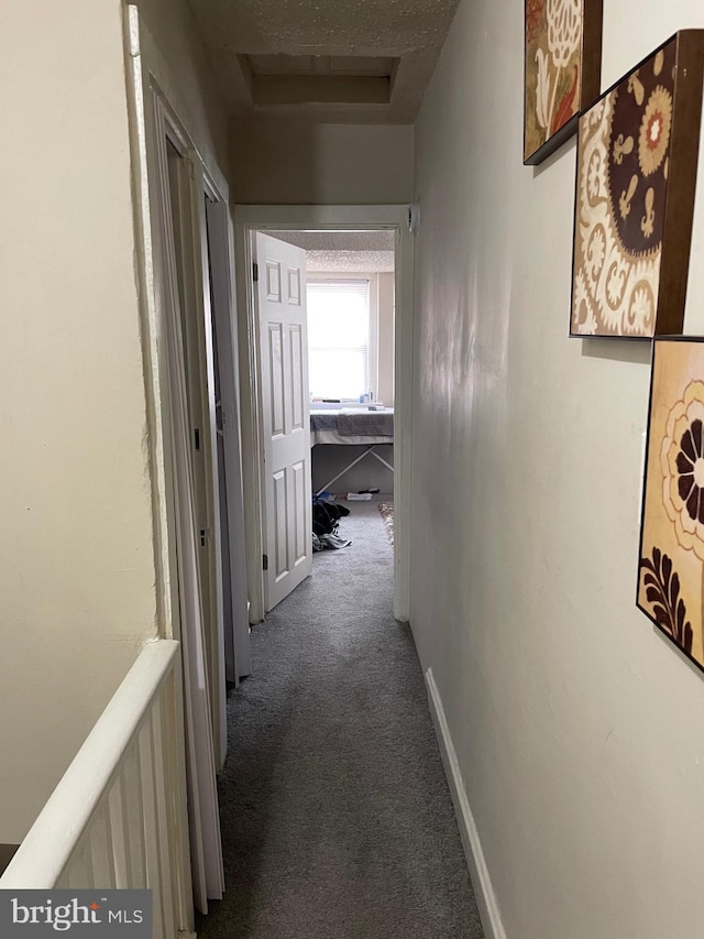 corridor featuring attic access, carpet flooring, and baseboards