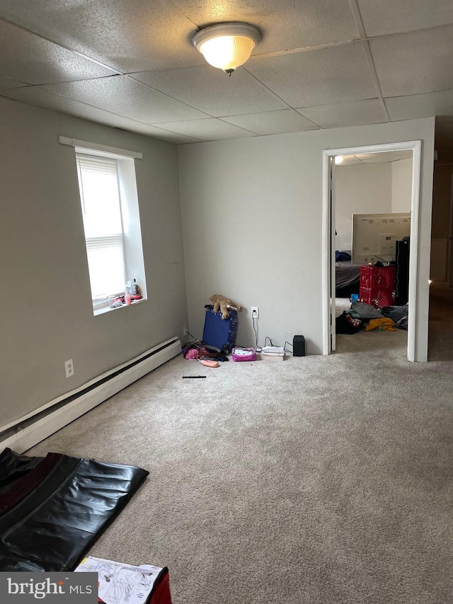 interior space featuring carpet floors, a baseboard heating unit, and a drop ceiling