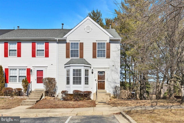 townhome / multi-family property with entry steps and a shingled roof