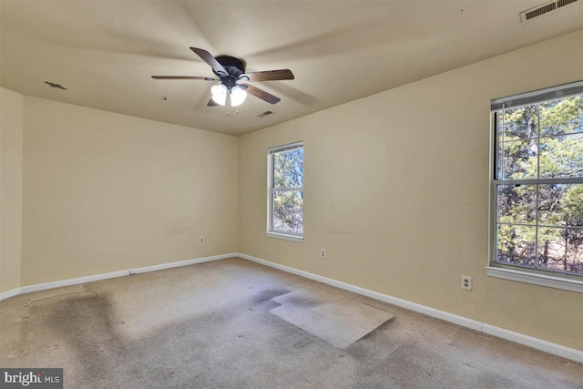 carpeted spare room with plenty of natural light, visible vents, ceiling fan, and baseboards