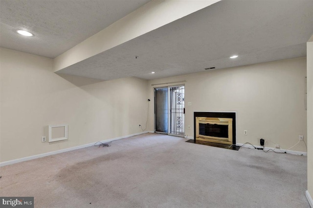 below grade area featuring carpet floors, a fireplace with flush hearth, visible vents, and baseboards