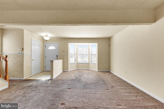 entryway with light colored carpet, stairway, and baseboards