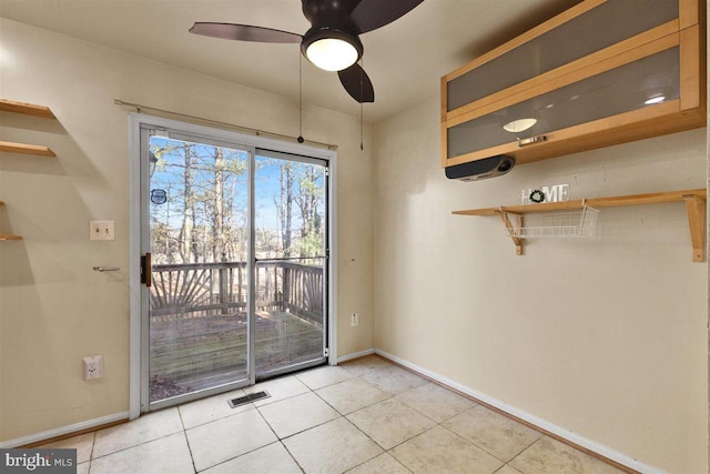 interior space featuring baseboards, visible vents, ceiling fan, and light tile patterned flooring