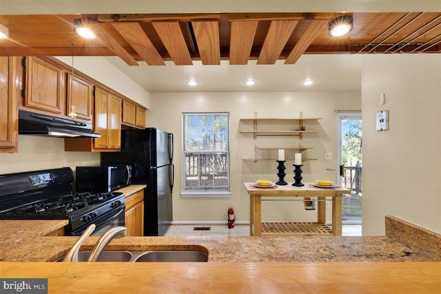 kitchen featuring under cabinet range hood, a sink, beamed ceiling, black appliances, and brown cabinetry