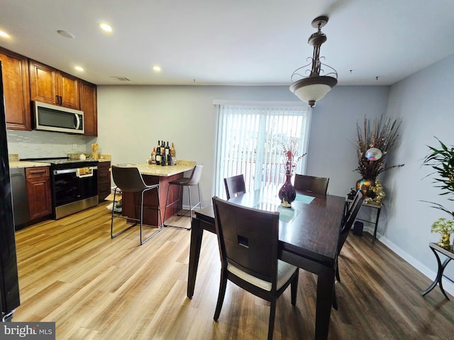 dining room with visible vents, baseboards, light wood-style flooring, a bar, and recessed lighting