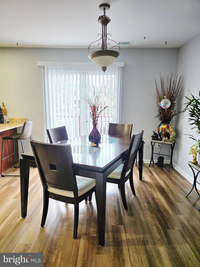 dining space with visible vents, baseboards, and wood finished floors