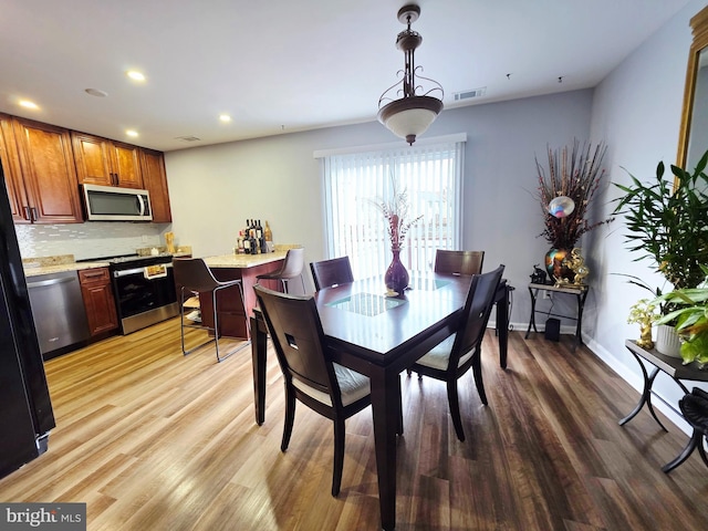 dining space with light wood-style flooring, visible vents, baseboards, and recessed lighting