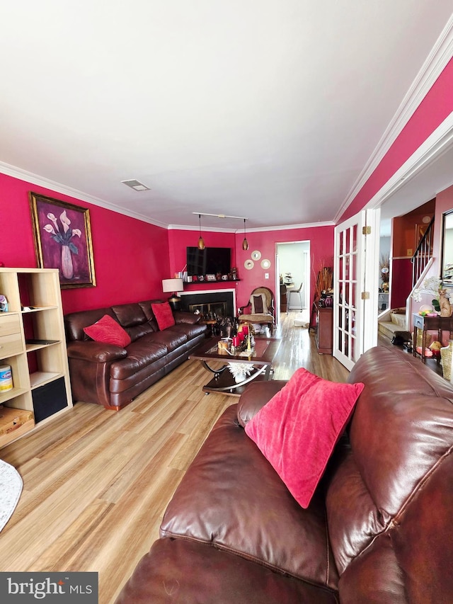 living area with crown molding, visible vents, wood finished floors, and french doors