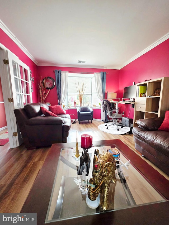 living area with ornamental molding, wood finished floors, and visible vents