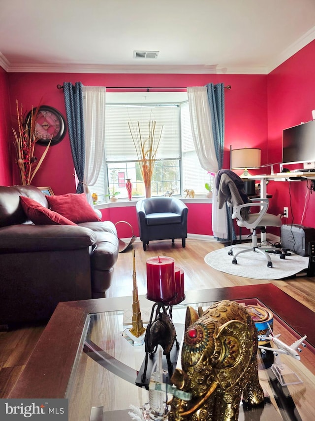 living area with ornamental molding, visible vents, and wood finished floors