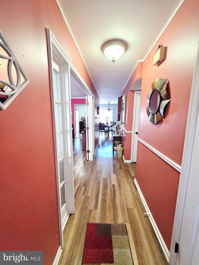 hallway featuring wood finished floors and baseboards