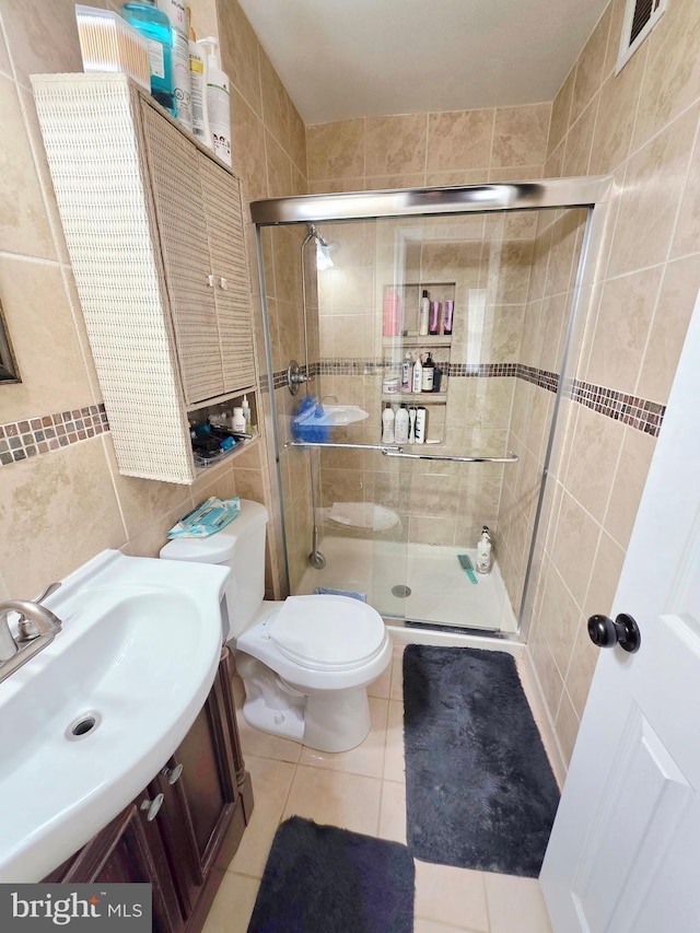 bathroom featuring a stall shower, visible vents, toilet, tile patterned floors, and a sink