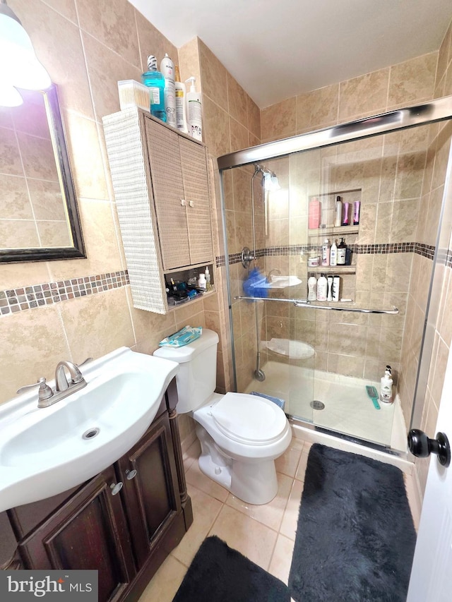 full bathroom featuring toilet, vanity, tile walls, tile patterned floors, and a stall shower