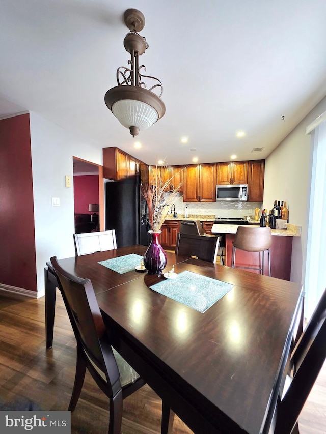 dining space with baseboards, wood finished floors, and recessed lighting