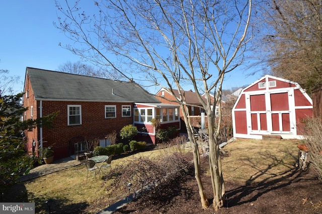 exterior space with a shed, an outdoor structure, and brick siding