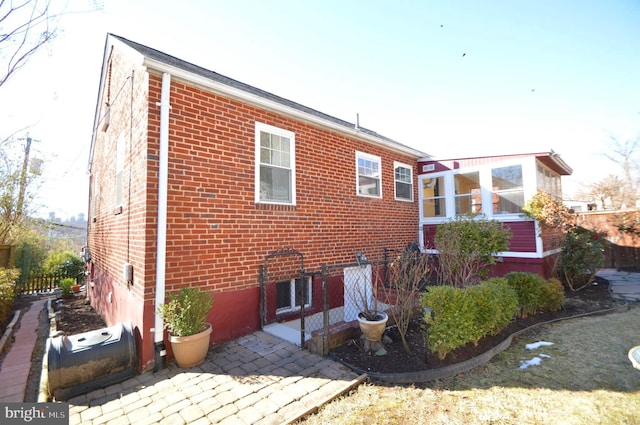 rear view of house with fence and brick siding