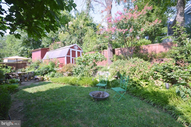 view of yard with a fire pit, a shed, an outbuilding, and a fenced backyard