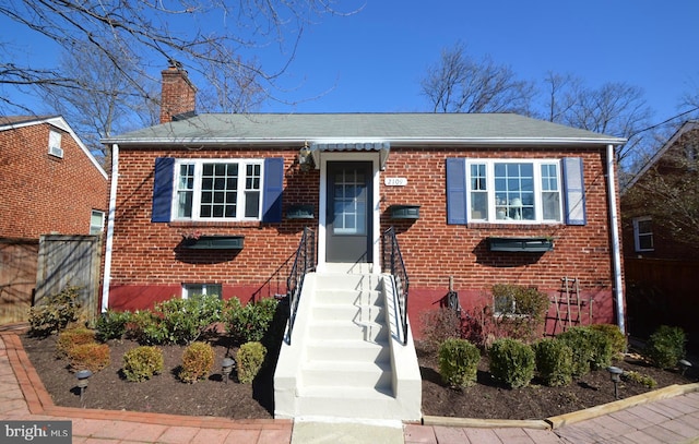 bungalow-style house with a chimney and brick siding