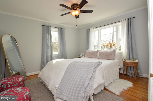 bedroom featuring a ceiling fan, crown molding, baseboards, and wood finished floors