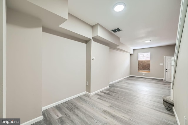 below grade area featuring light wood-type flooring, baseboards, and visible vents