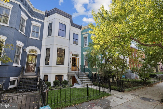 view of property featuring a fenced front yard, a front lawn, and brick siding