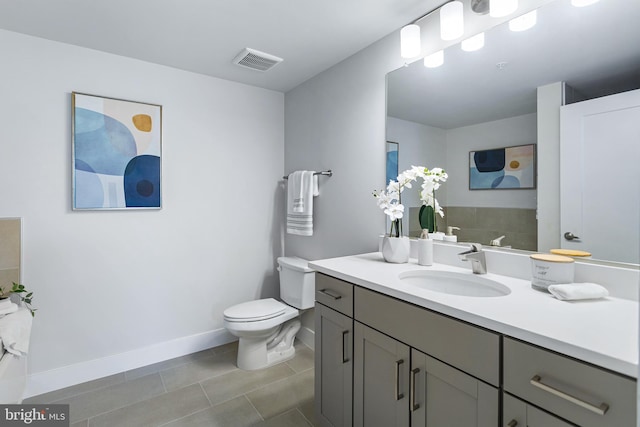 bathroom featuring toilet, vanity, visible vents, baseboards, and tile patterned floors