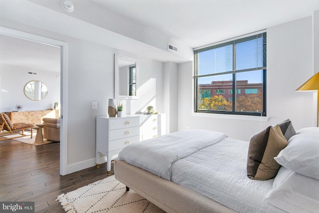 bedroom with dark wood-style floors, visible vents, and baseboards