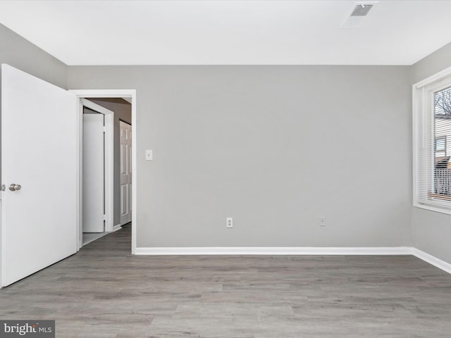 unfurnished room with baseboards, visible vents, and light wood finished floors