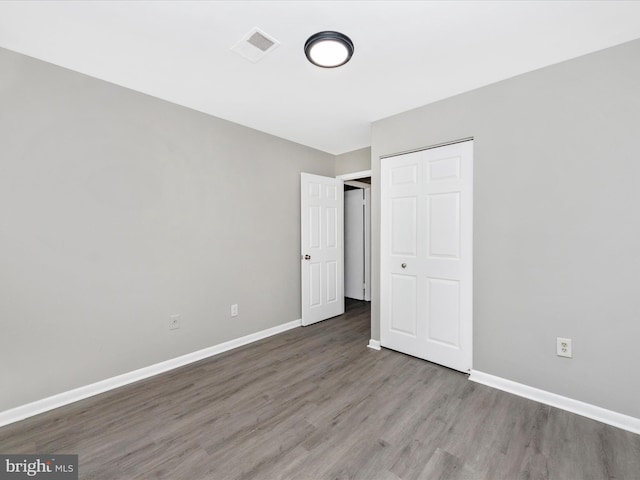 unfurnished bedroom featuring baseboards, visible vents, and wood finished floors