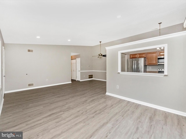 unfurnished living room featuring light wood-style floors, visible vents, baseboards, and a ceiling fan