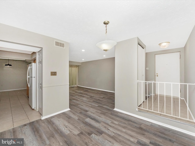 empty room with wood finished floors, visible vents, and baseboards