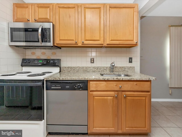 kitchen with tasteful backsplash, light stone counters, stainless steel appliances, a sink, and light tile patterned flooring