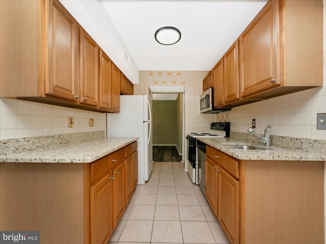 kitchen featuring white appliances, a sink, light stone counters, and brown cabinets