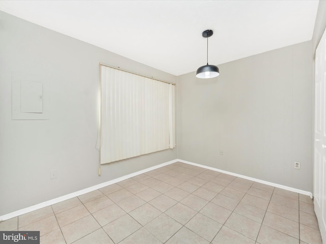 unfurnished room with light tile patterned flooring, electric panel, and baseboards