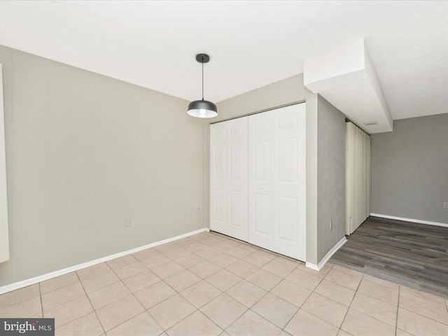 unfurnished bedroom featuring a closet, light tile patterned flooring, and baseboards