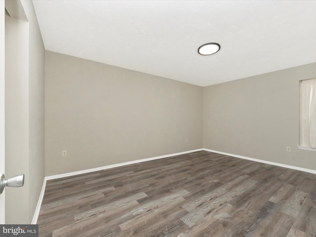 unfurnished room featuring dark wood-type flooring and baseboards