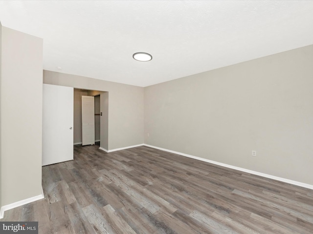 spare room with baseboards and wood finished floors